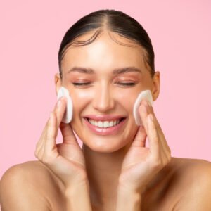 daily skincare excited young lady cleaning face with cotton pads smiling doing skin care routine.jpg